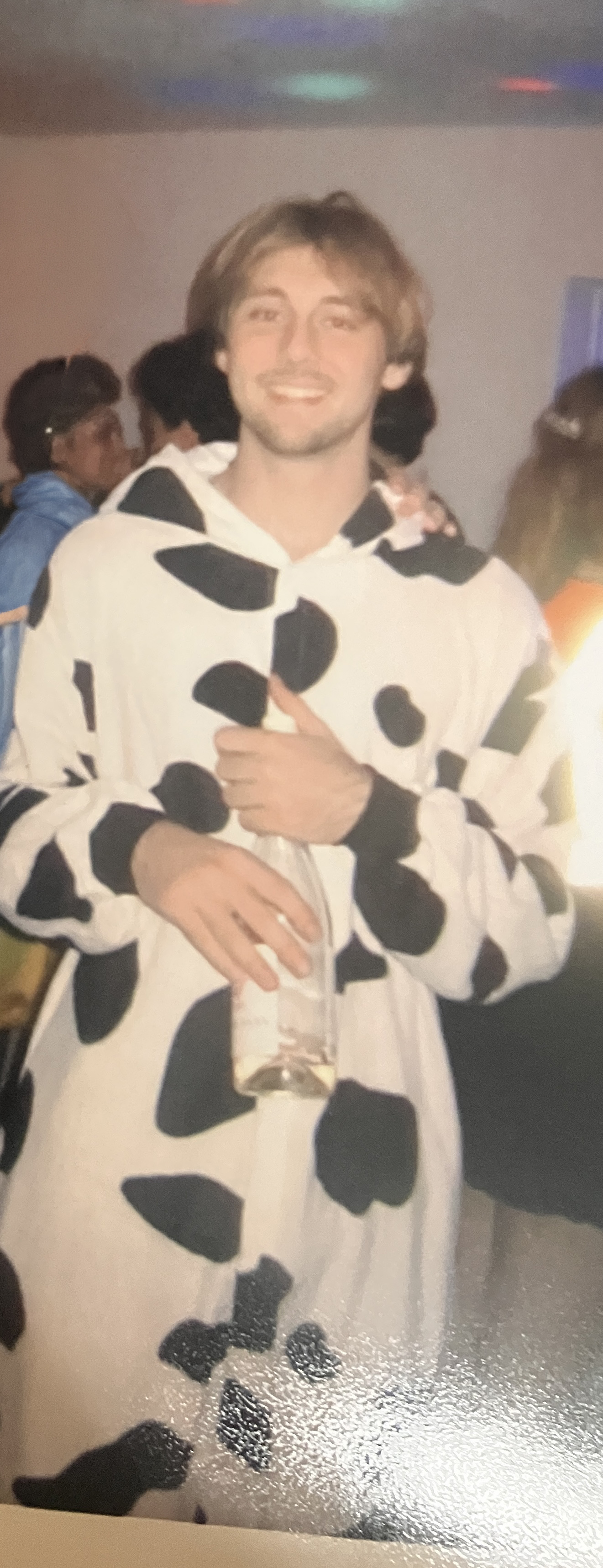 Alex Everett smiling in a cow-print costume.